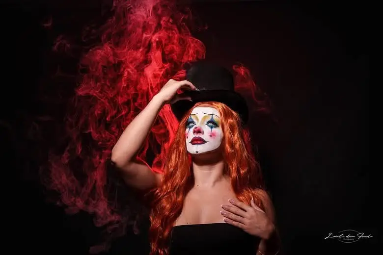 Maquillage Halloween de clown avec chapeau noir et fumée rouge